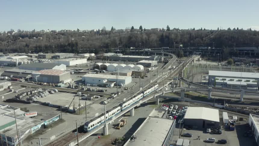 Train travels on railroad through industrial part of city
