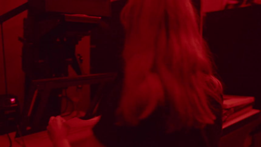 Woman is working with photographs in a darkroom