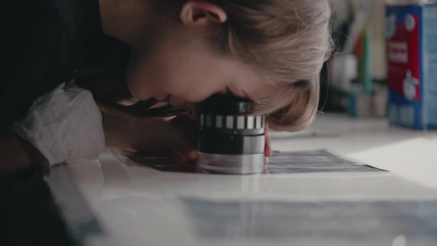Someone is looking through a magnifier at negative pictures
