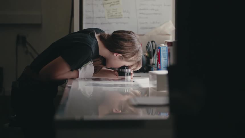 A woman looks at film negatives at a workbench