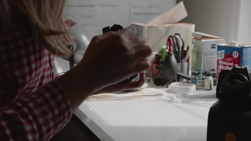 A woman loads and adjusts the film for a camera