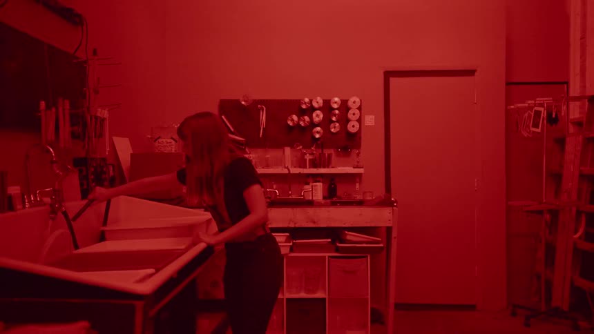 A woman develops film in a darkroom