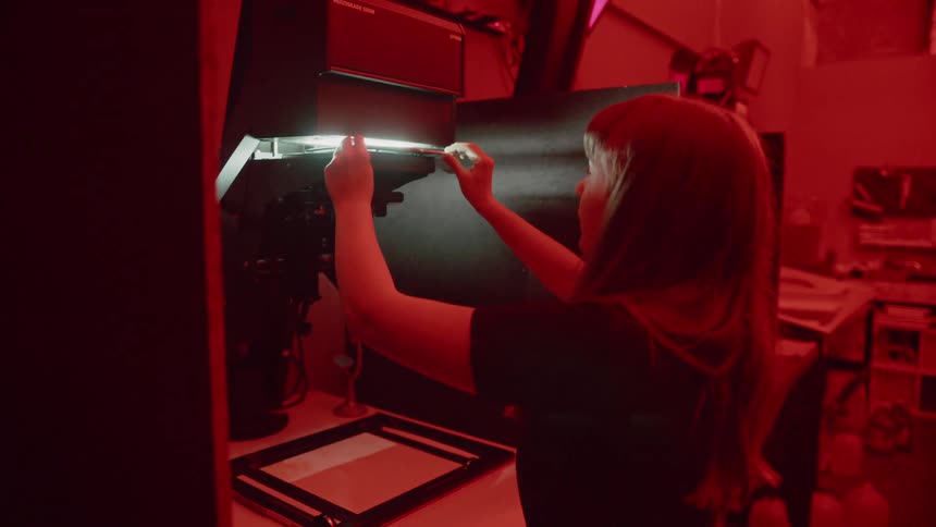 A woman in a dark room inserts a slide into a machine
