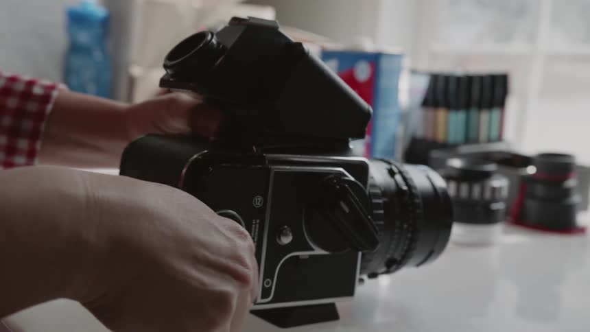 A person is winding the film inside a medium format camera inside a studio in daylight
