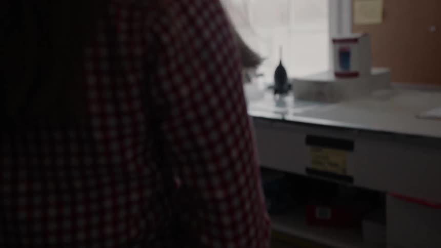 A woman is carrying a camera over to a desk