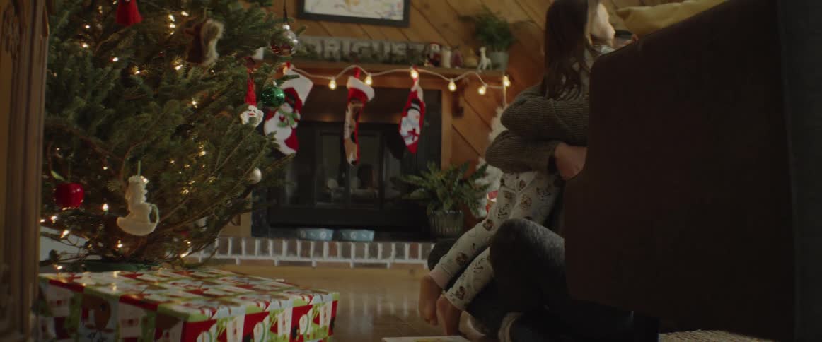 Woman and girl hug next to a christmas tree