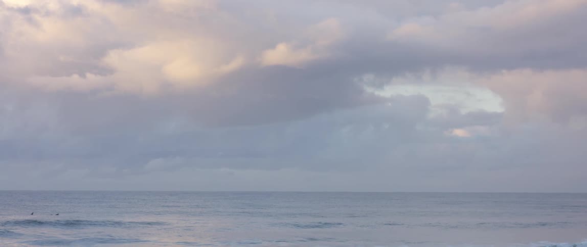 Clouds hover over an expanse of the ocean