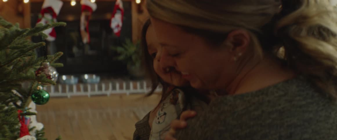Mother and daughter are hugging next to christmas tree