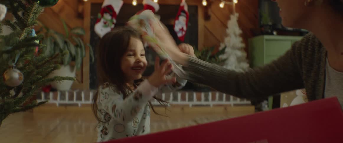 A mother and her young daughter are playing in a living room on christmas day