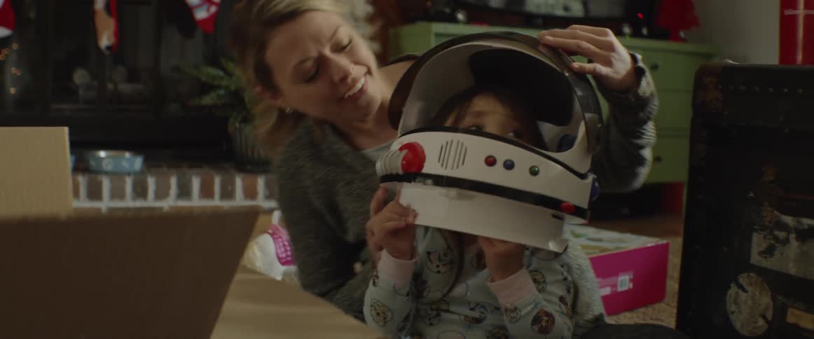 Woman smiles at a child wearing a toy astronaut helmet