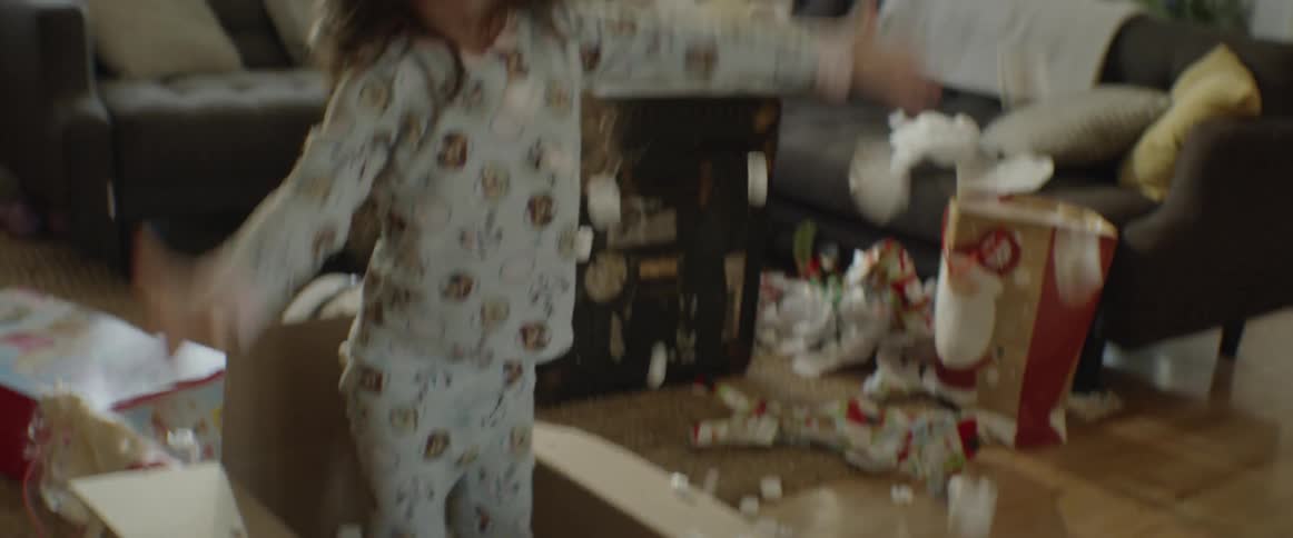 A young girl plays with packing peanuts in a cardboard box