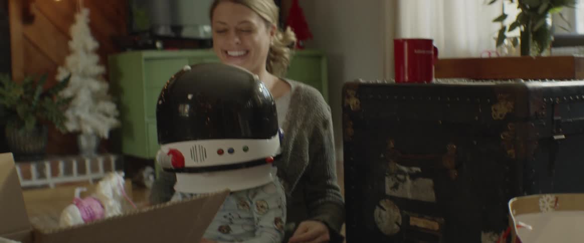 Woman puts a toy astronaut helmet on a girl's head