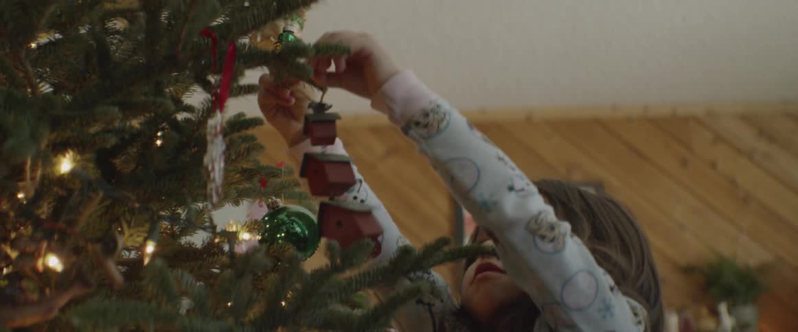 A girl hangs ornaments on a christmas tree