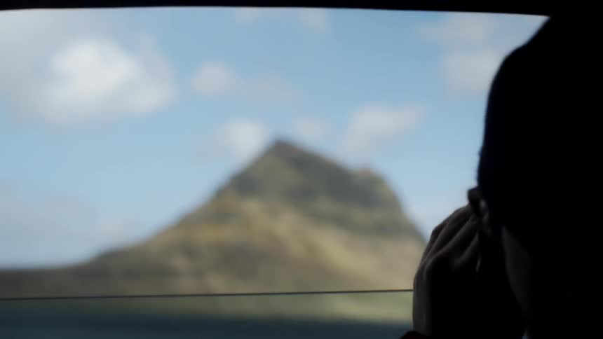 Person takes photograph of mountain from car window