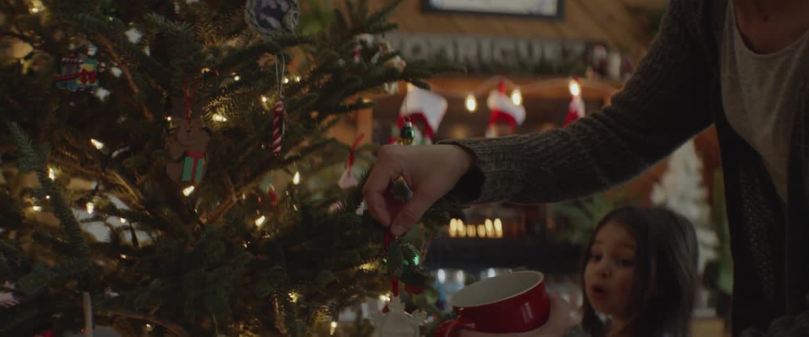 Woman hangs ornament on christmas tree