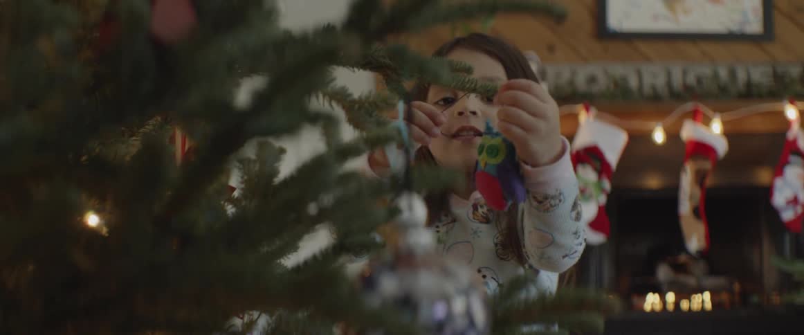 A small child is putting christmas ornaments on a tree
