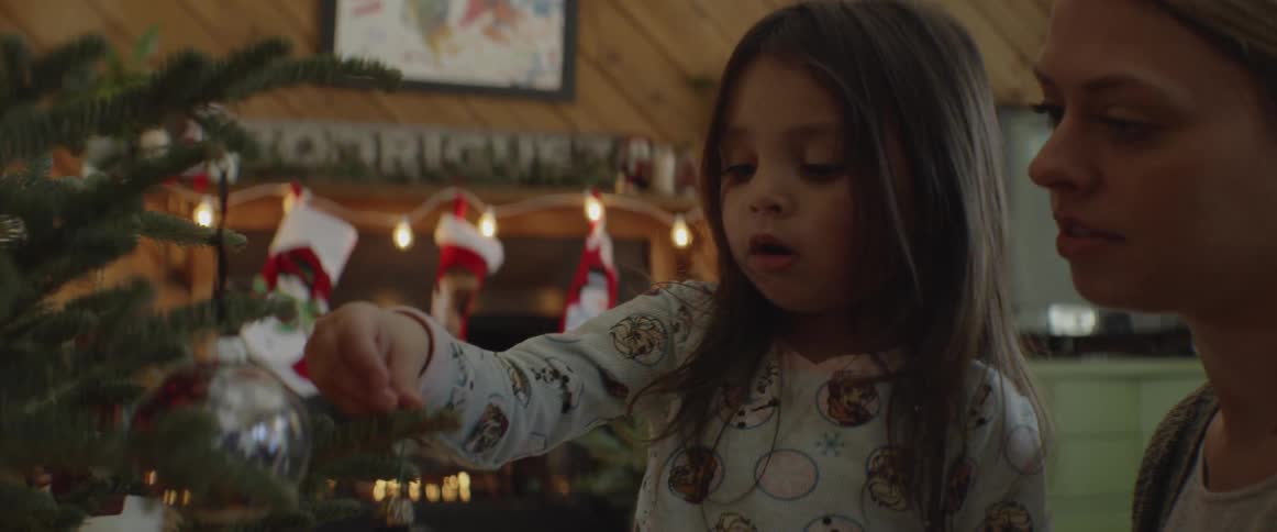 A girl hangs an ornament on the christmas tree