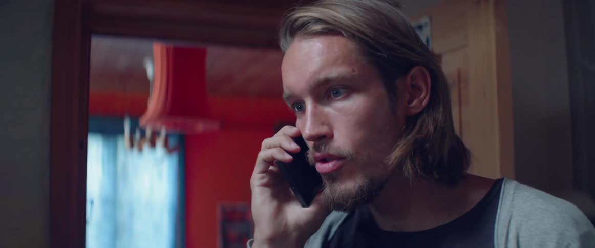 A concerned man looks wide eyed while talking on his mobile phone indoors.