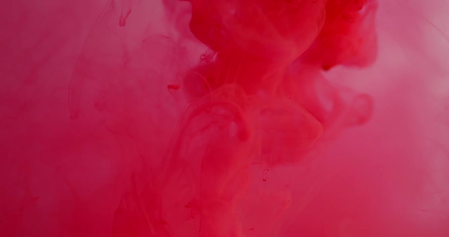 Red dye is falling into and spreading out in a liquid solution