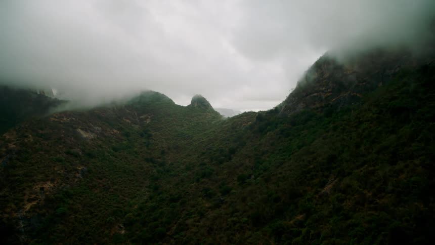 Clouds covering the sky over green mountains