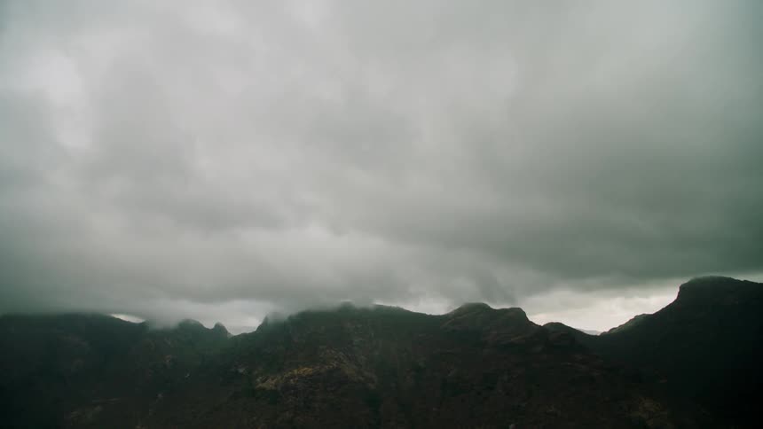 Thick clouds hovering and flowing over mountains
