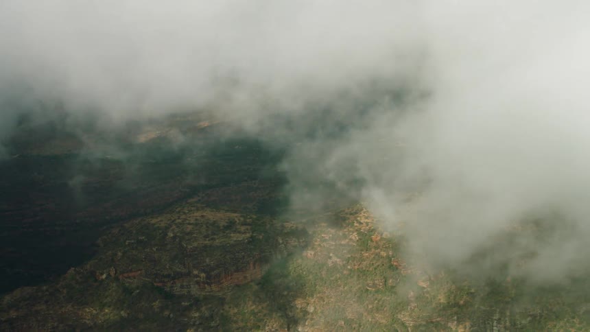 Clouds covering green mountains