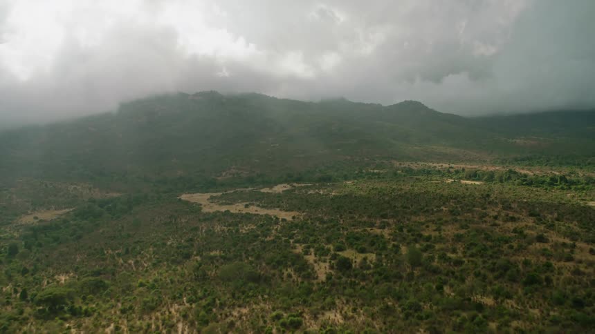 Sunlight is streaming through clouds over remote hills during the day