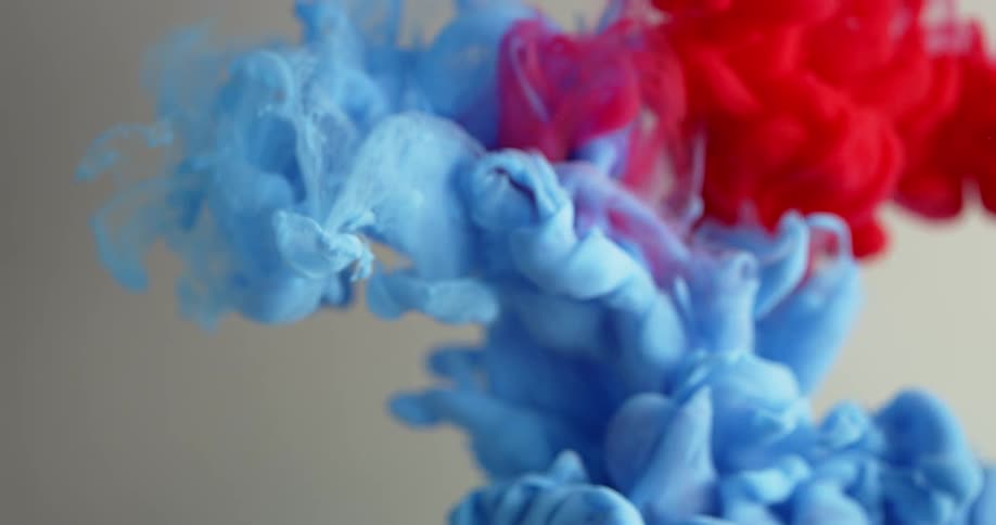 Blue and red liquid mix together in clear liquid