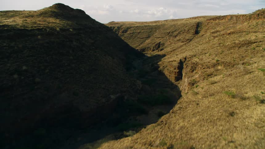 A shadow is covering a ravine in a natural setting in daylight