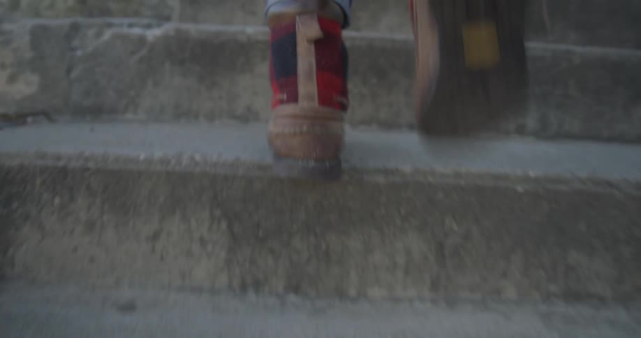Feet walking quickly up a stone staircase