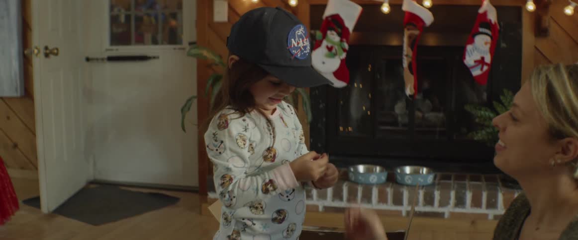 A woman puts a nasa hat on a little girl