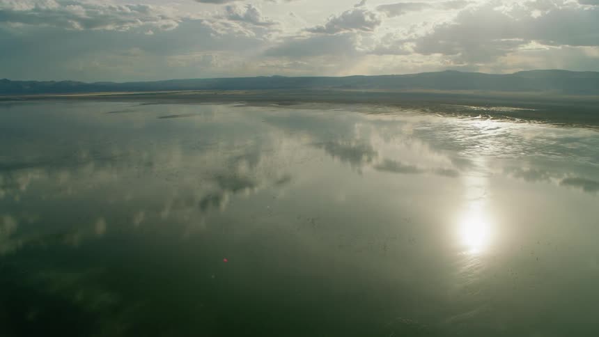 Reflection of clouds and sun on still body of water