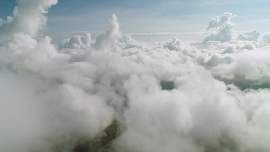 The sky is full of large clouds covering the green below