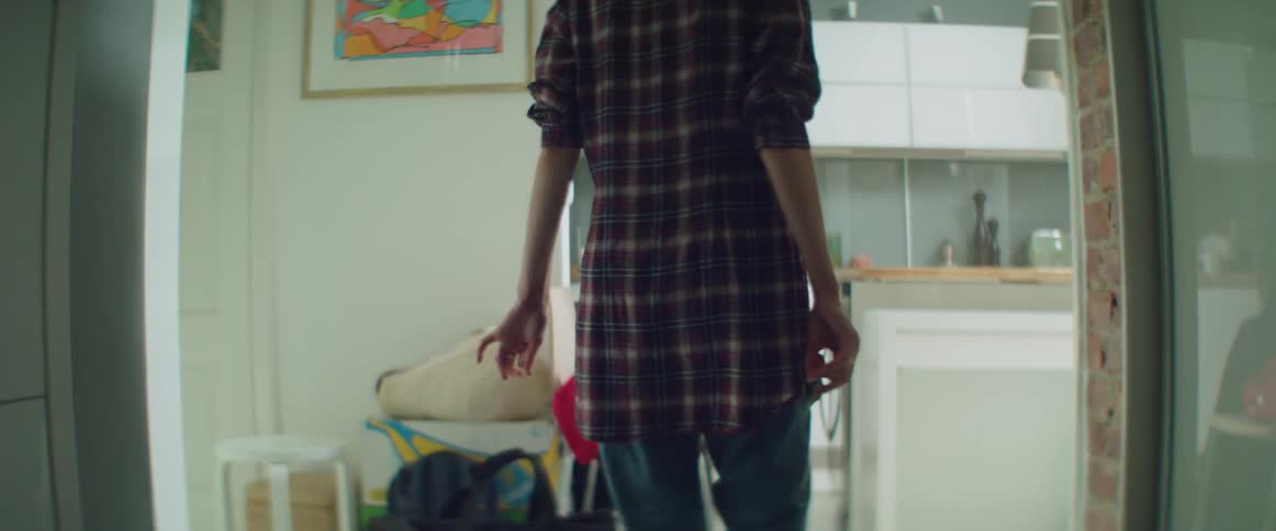 An anxious woman paces around a messy apartment filled with moving boxes.