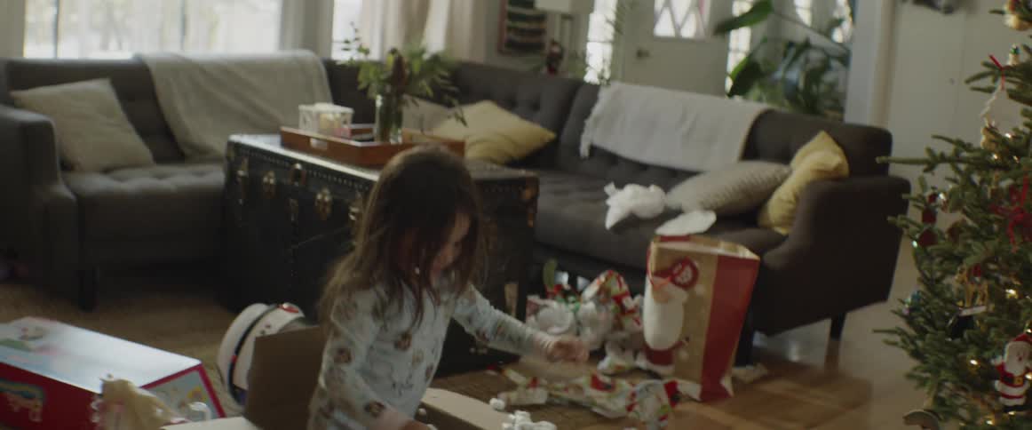 Child throws packing peanuts out of a box and sits down in it