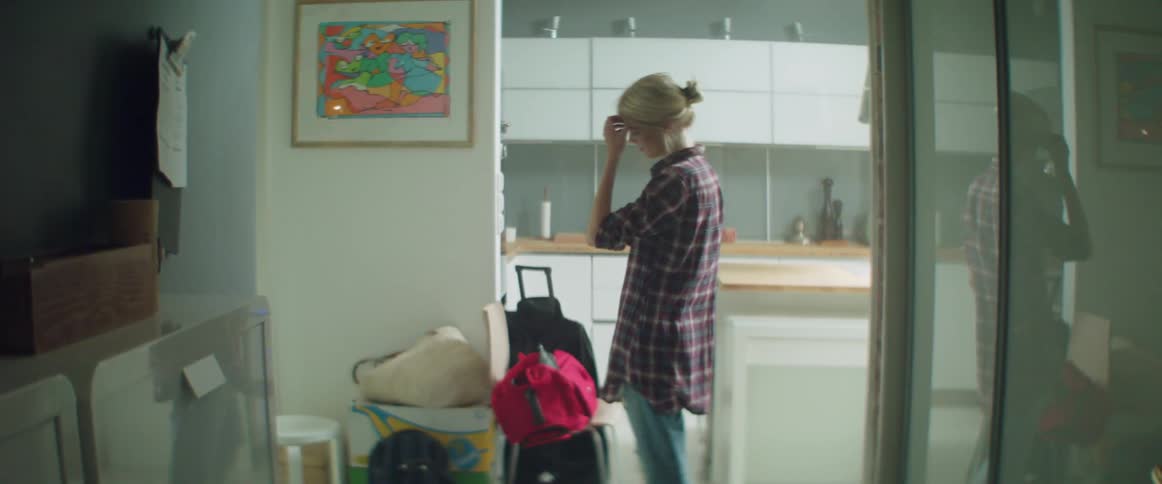 A woman walks into a messy apartment carrying suitcases during relocation day.
