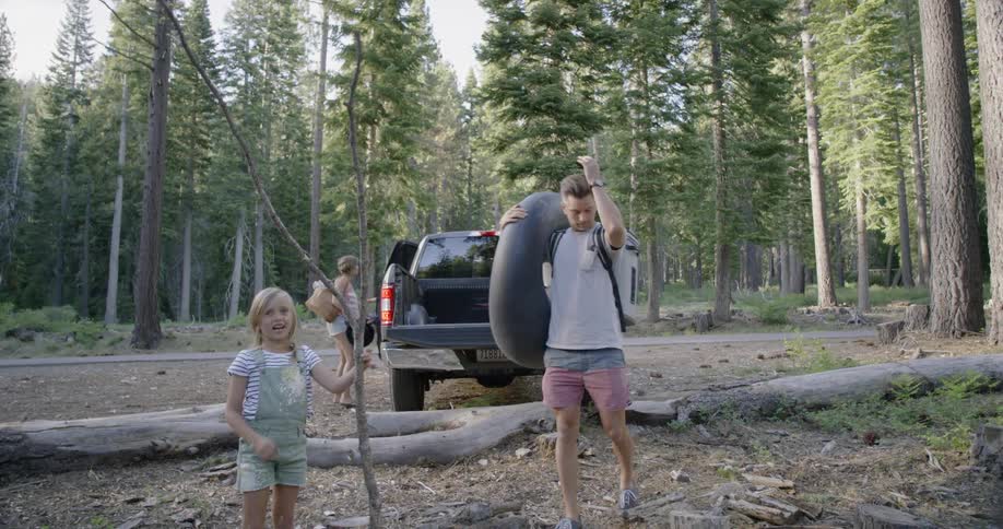 A family unloads a truck in the woods