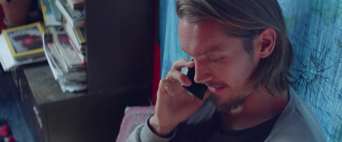 A man near a bookcase talks on the phone