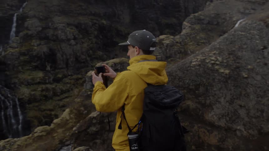 A man takes photos of nature from on top of a cliff