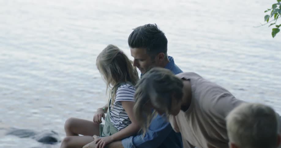 Family sits down together next to lake