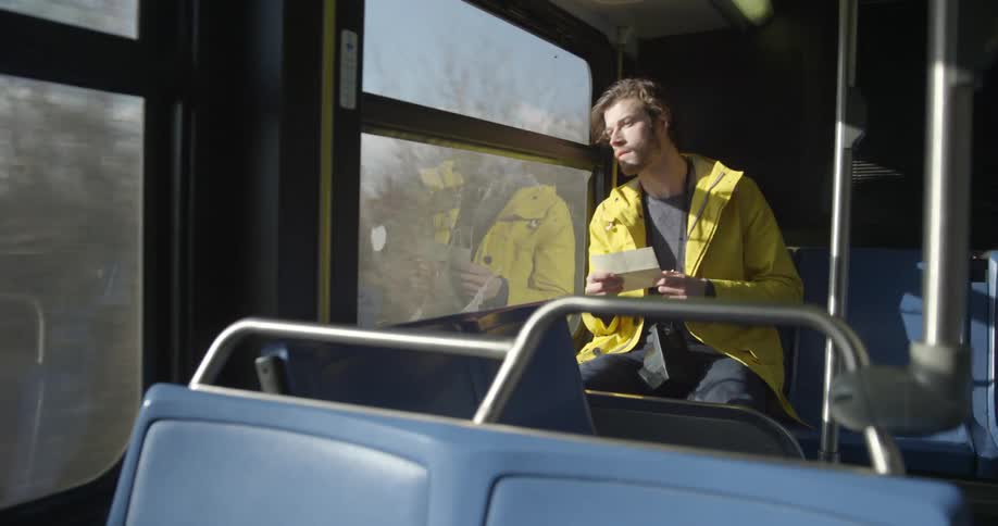 A man rides a bus and reads a piece of paper