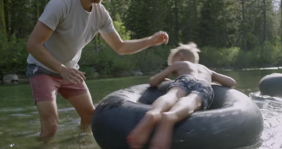 A man spins a child in the water on the inner tube