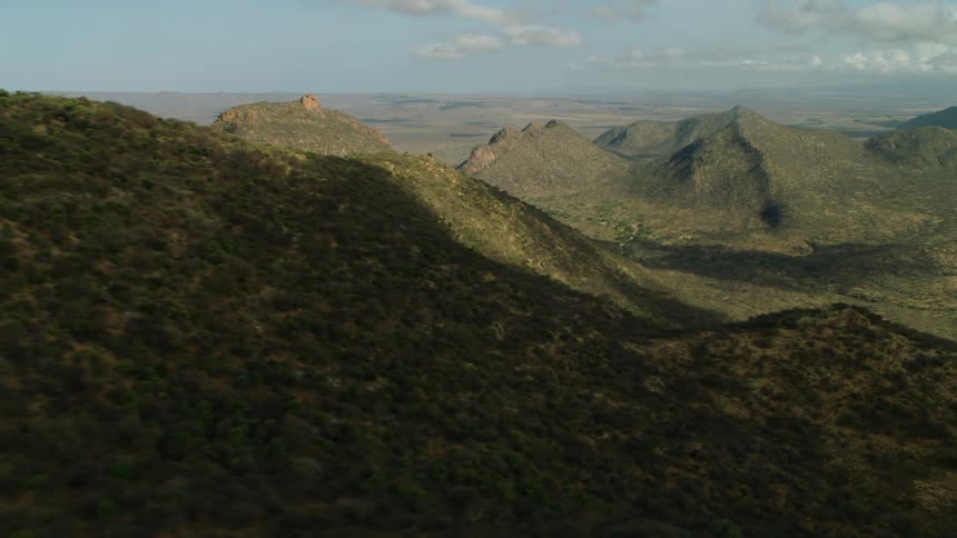 Clouds are casting shadows on a mountain landscape during the day