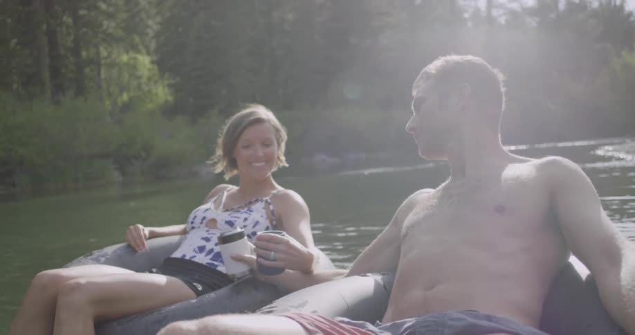 A man and woman are sitting on some rafts in a creek