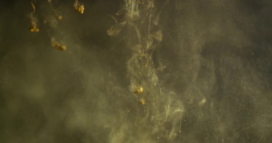 A gold dye is falling into a liquid solution and dissipating