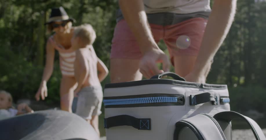 Man unzips a lunch box outside on a sunny day