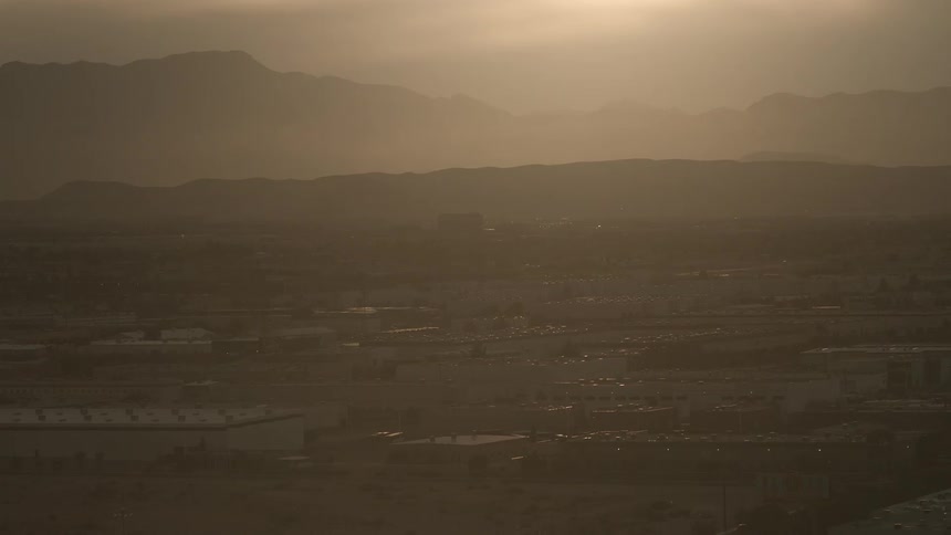 Haze is hanging in the air above an industrial area and foothills