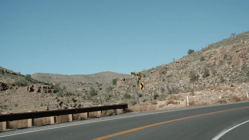A barrier and street signs line the side of a road