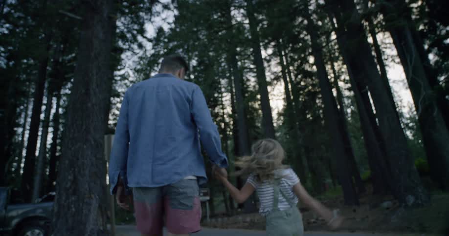 A man and small girl are walking down the street holding hands