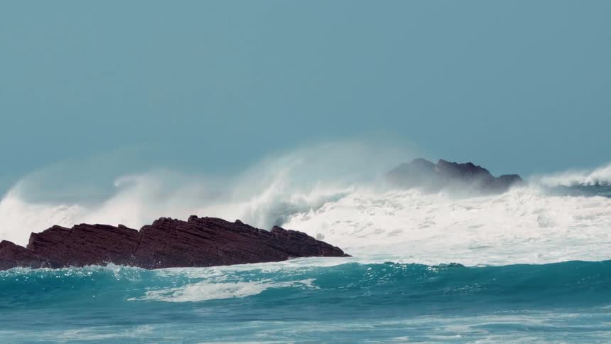 Waves crash onto a rock formation in the ocean